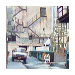 A maze of fire escape stairs frame a white pickup truck and an alley full of construction detritus