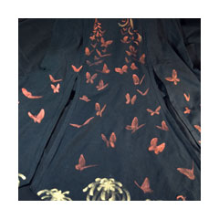 a spreading black skirt painted with copper and gold butterflies and chrysanthemums