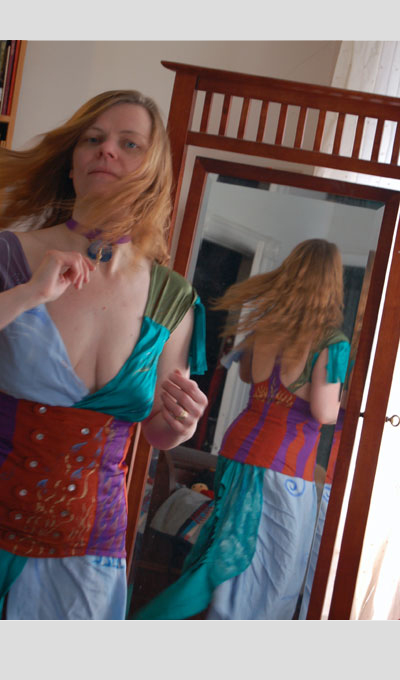 A photograph of a woman turning in front of a mirror, wearing the garments