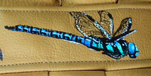 A close-up of a lifesized blue dragonfly painted in flight seen from the side