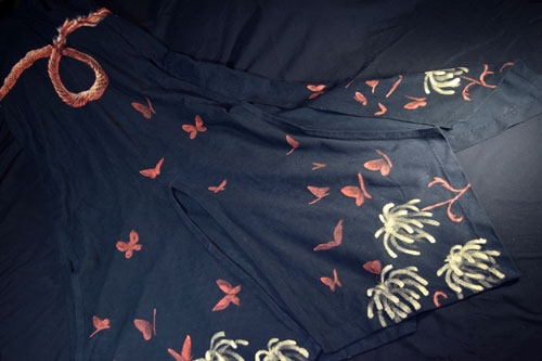 The back of the skirt on the dress, showing panels and painting of chrysantehemum-firework forms and butterflies and a looped illusionistic belt